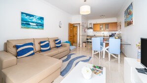 Een woonkamer met een bank, een salontafel en een eethoek met stoelen en een tafel.