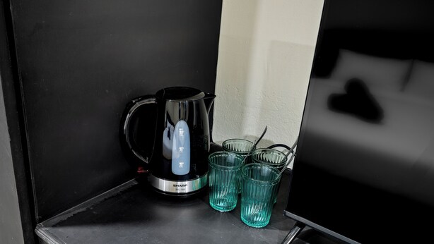 Una cafetera negra y dos vasos de vidrio sobre una encimera negra.