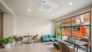 A modern living room with a sofa, chairs, a table, and a potted plant. - Simply Stay Chaweng (Koh Samui)