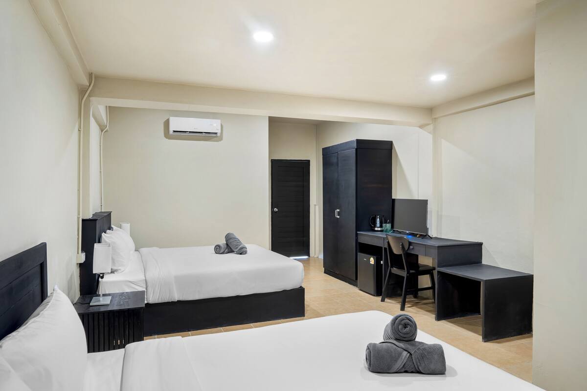 Habitación de hotel con dos camas, un escritorio, un armario y un equipo de aire acondicionado.