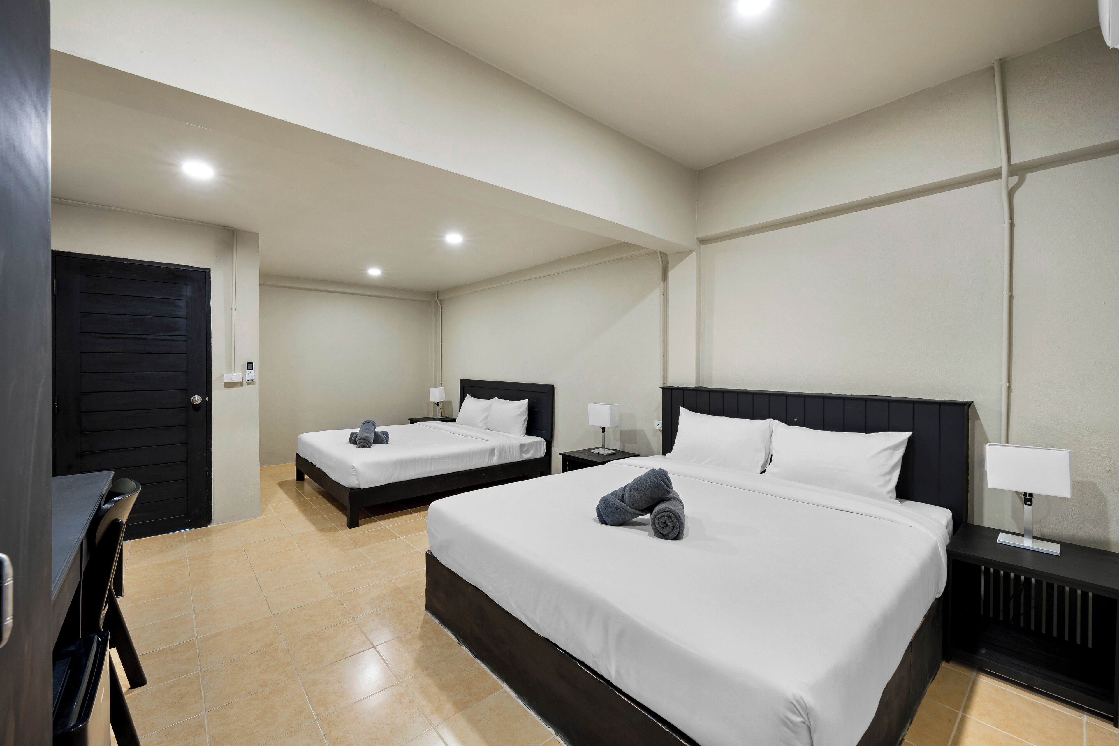A hotel room with two beds, a desk, and a chair.