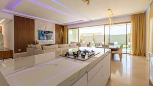 A modern kitchen with a marble countertop, a built-in stove, and a dining area with a table and chairs. - Superb Marrakech villa with heated pool (Marrakech)