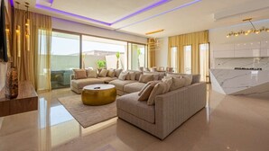A modern living room with a sectional sofa, a round coffee table, and a kitchen area with marble countertops. - Superb Marrakech villa with heated pool (Marrakech)