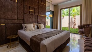 A modern bedroom with a large bed, a view of a garden, and a chair. - Superb Marrakech villa with heated pool (Marrakech)