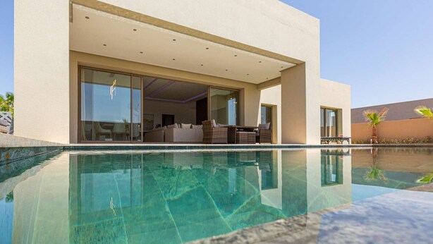 A modern house with an infinity pool, large glass doors leading to an outdoor living area, and a clear view of the pool. - Superb Marrakech villa with heated pool (Marrakech)