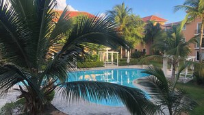 A swimming pool surrounded by palm trees and a building with a red roof. - Your Private Getaway Oasiss (Punta Cana)