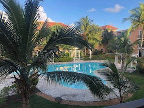 Una piscina rodeada de palmeras y un edificio con techo rojo.