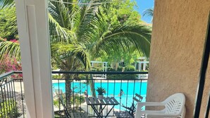 A balcony with a pool view, outdoor furniture, and a tiled floor. - Your Private Getaway Oasiss (Punta Cana)