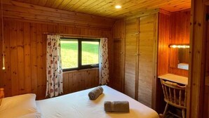 Una camera in legno con un letto, una scrivania e una finestra con tende.