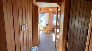 Un corridoio in legno con termosifone, un tavolo e sedie, e una porta che dà su un'altra stanza.