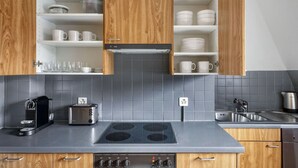 A modern kitchen with wooden cabinets, a built-in stove, a toaster, and a kettle.