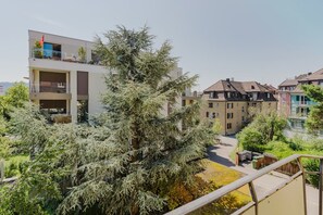 Een woongebouw met een balkon, een boom op de voorgrond en een heldere lucht.