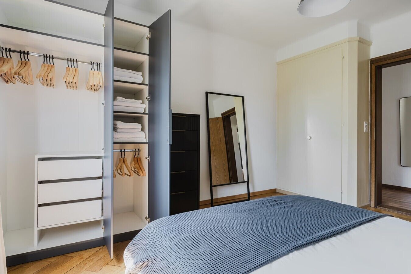 Ein Schlafzimmer mit einem Bett, einem Kleiderschrank und einem Spiegel.