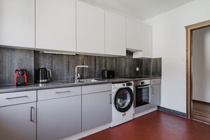 A modern kitchen with a washing machine, a coffee maker, and a microwave.