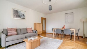 A modern living room with a sofa, coffee table, and dining area.