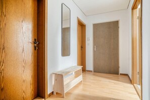 A hallway with wooden flooring, a bench, a door, and a large mirror on the wall. - 3-BR in Wipkingen · parking · tram nearby (Zürich)