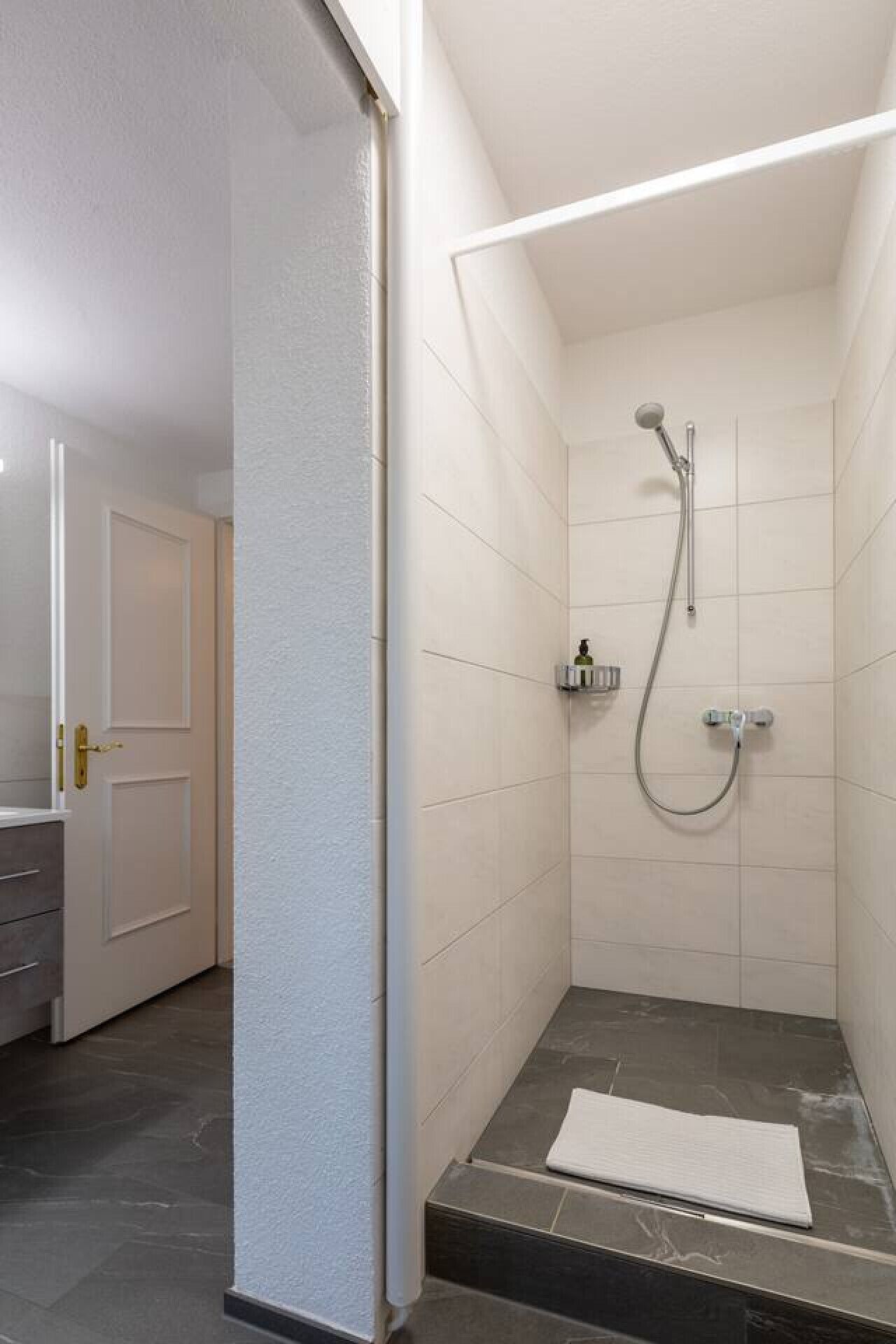 A small, modern bathroom with a shower, a toilet, and a sink.