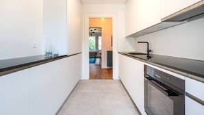 Une cuisine moderne avec des armoires blanches, des plans de travail noirs et des appareils en acier inoxydable.
