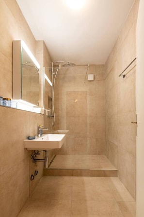 Un baño moderno con ducha, lavamanos y espejo.