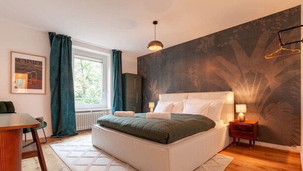 Une chambre moderne avec un grand lit, un bureau et une fenêtre avec des rideaux.