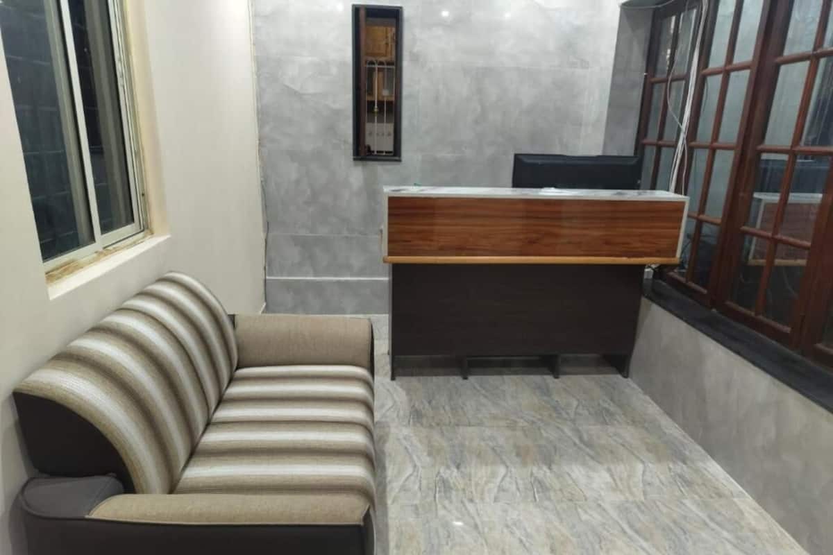 Quarto moderno com sofá listrado, escrivaninha de madeira e piso de mármore.