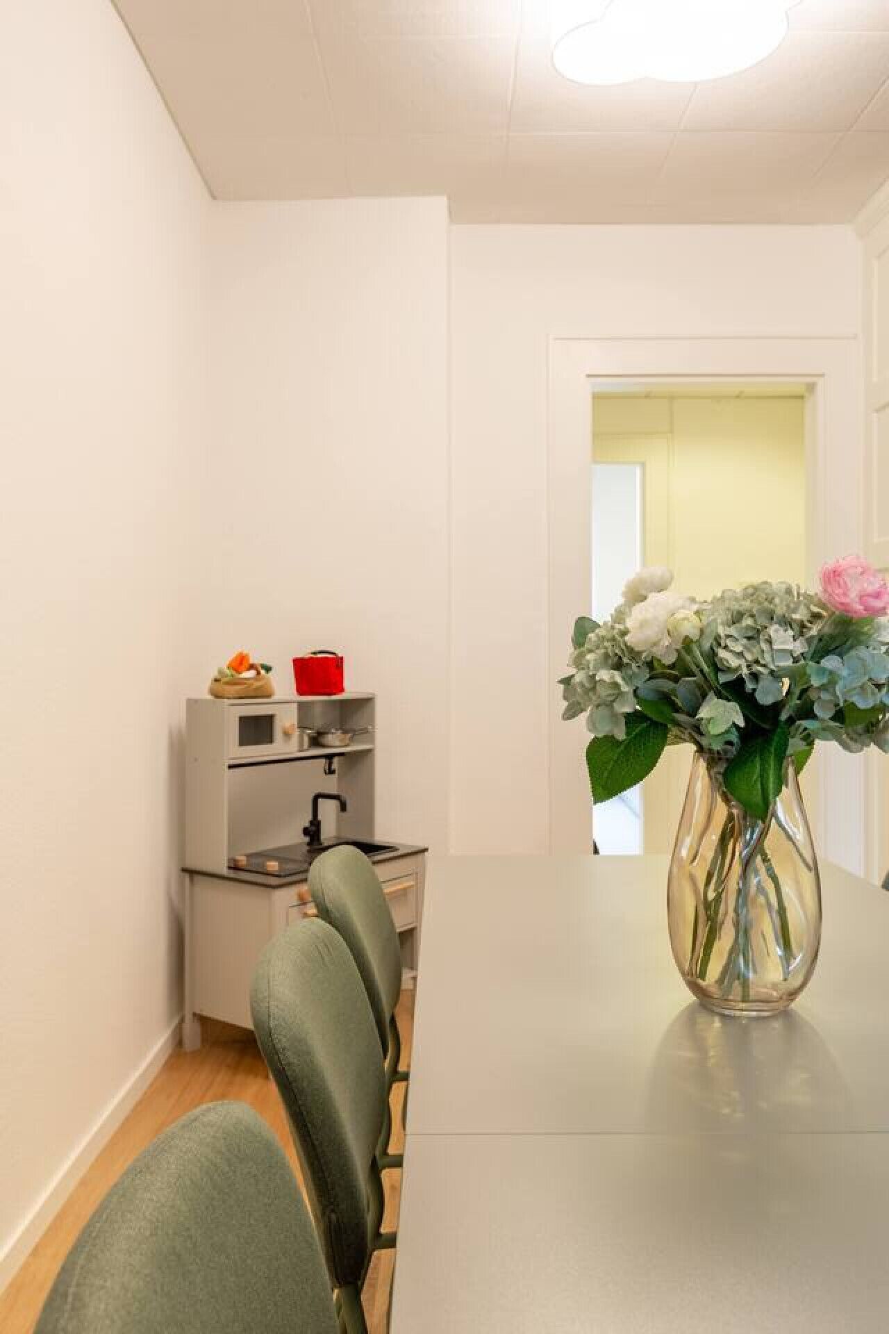 Une cuisine moderne dotée d’un four et d’un micro-ondes encastrés, une table à manger avec des chaises, et un vase avec des fleurs placé sur la table.