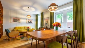 A dining area with a wooden table and chairs, a yellow sofa, and a green vase with flowers. - Vintage 2-BR in central Zürich · sleeps 5 (Zürich)