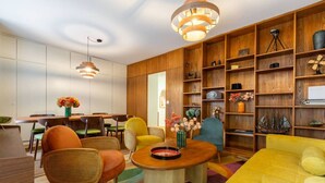 A modern living room with a dining area, wooden shelving with decorative items, and a colorful rug. - Vintage 2-BR in central Zürich · sleeps 5 (Zürich)