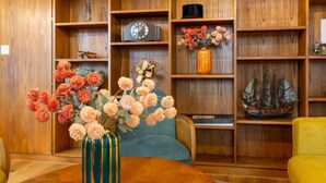 A wooden bookshelf with various decorative items, including a clock, flowers, and a ship model. - Vintage 2-BR in central Zürich · sleeps 5 (Zürich)