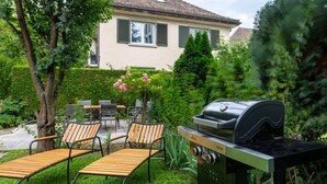 Une terrasse extérieure avec des chaises en bois et un barbecue.