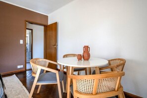 Un coin repas avec une table ronde, quatre chaises en bois et un mur blanc.