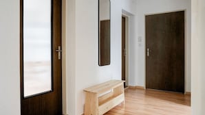 Ein Korridor mit einer hölzernen Bank, einer Tür mit einem Spiegel und einer dunklen Holztür.
