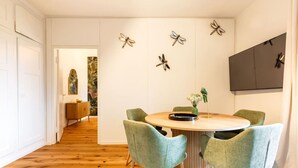 A dining area with a round table, four green chairs, and decorative dragonfly wall art. - Stylish 3-BR design flat with terrace · Kreis 6 (Zürich)