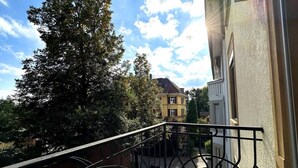 A balcony with a metal railing overlooking a courtyard with a building in the background. - Stylish 3-BR design flat with terrace · Kreis 6 (Zürich)
