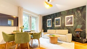 A modern living room with a sofa, a dining table with chairs, and artwork on the walls. - Stylish 3-BR design flat with terrace · Kreis 6 (Zürich)