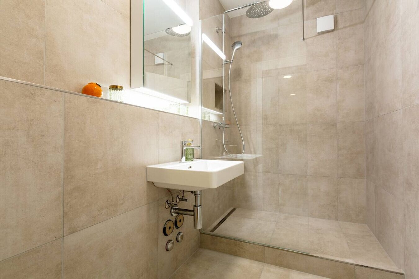Une salle de bain moderne avec un lavabo, un miroir et une douche.