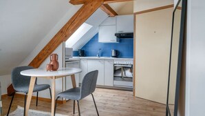 Une petite cuisine moderne avec un plan de travail blanc, un pare-feu bleu et une poutre en bois au plafond.