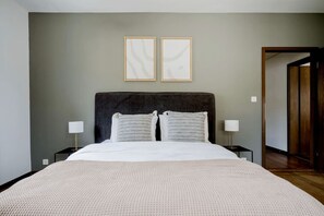 A bedroom with a large bed, two bedside tables, and two framed pictures on the wall. - Bright 2-BR in Wipkingen — balcony, garden & tram nearby (Zürich)