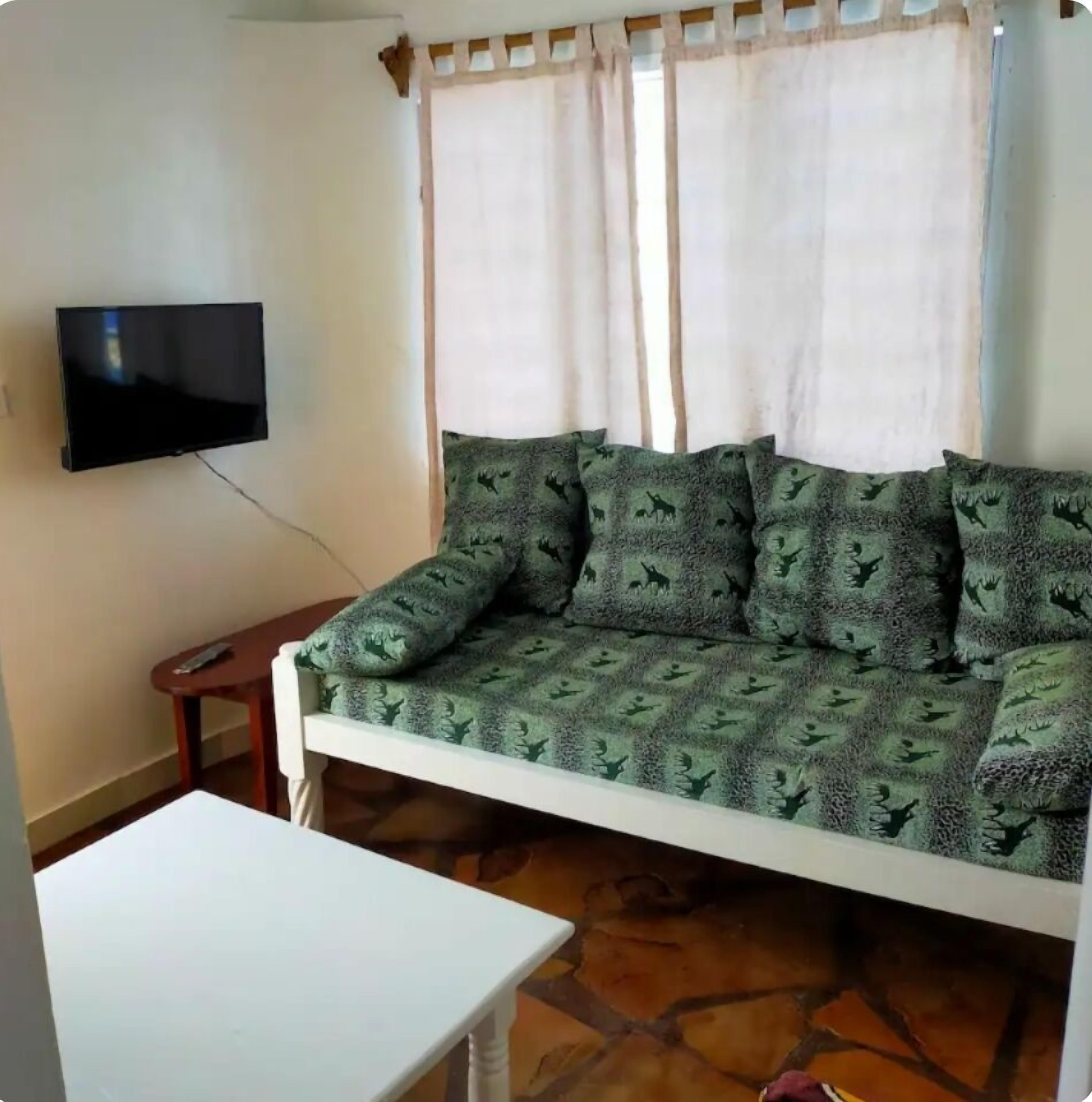 A living room with a sofa, a TV mounted on the wall, and a small table.