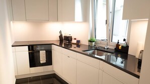 Une cuisine moderne avec des meubles blancs, un plan de travail noir et un évier en acier inoxydable.