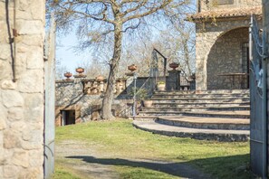 Un edificio de piedra con una escalera que conduce a una puerta, rodeado de hierba y árboles.