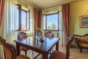 A dining room with a wooden table, four chairs, and a vase with flowers. - Il Casale del Sughereto (Bolsena)
