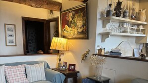 A cozy living room with a wooden ceiling, a sofa, a coffee table, and a bookshelf with decorative items.