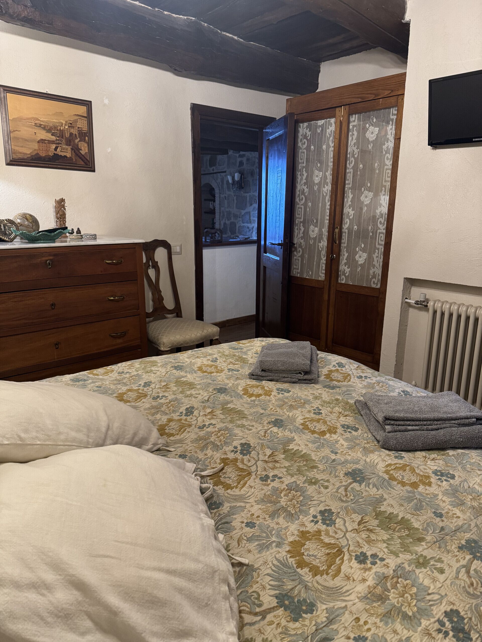A bedroom with a bed, a dresser, a chair, and a window with curtains.