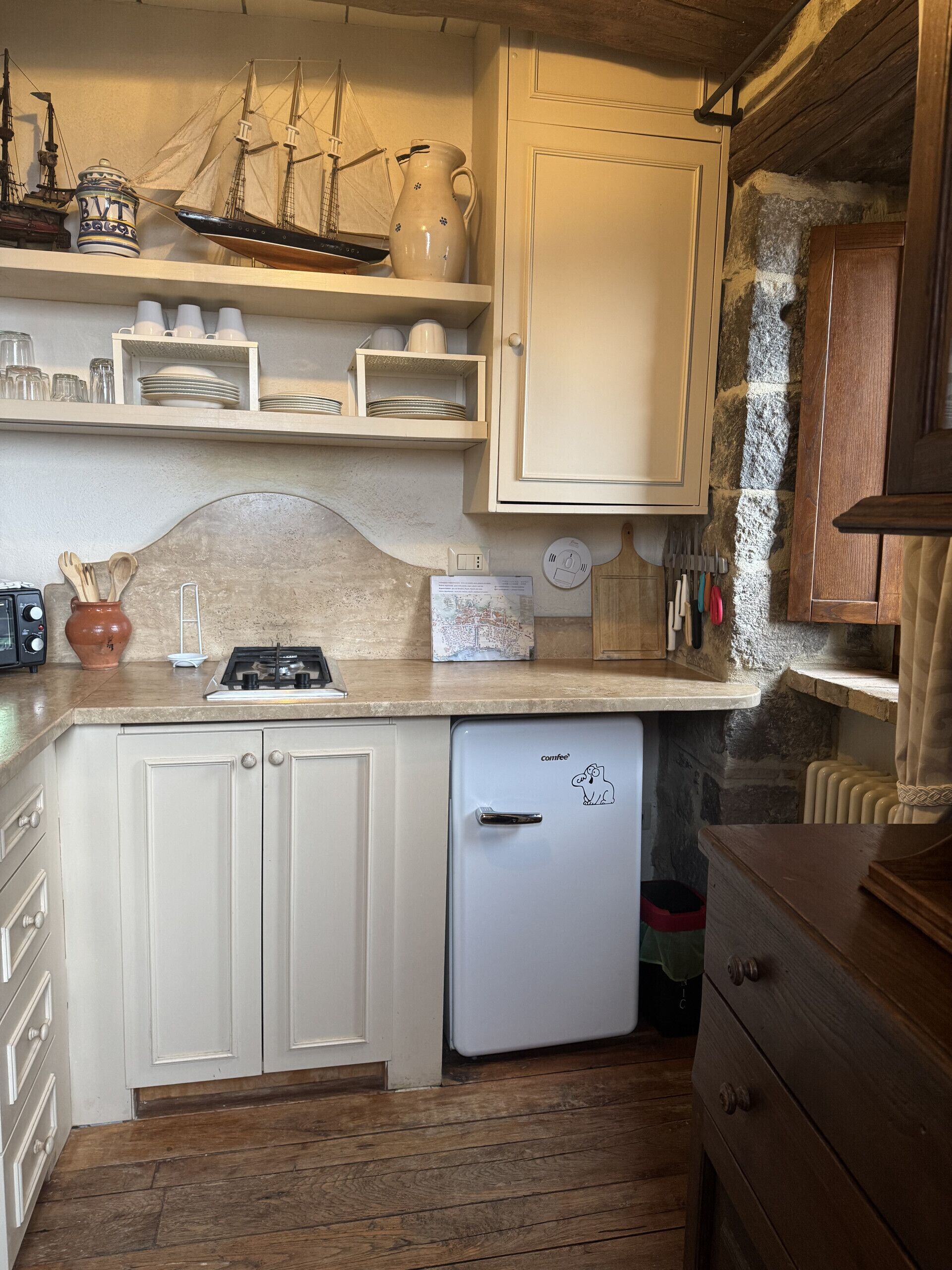 A compact kitchen with white cabinetry, a small refrigerator, and a wooden countertop.