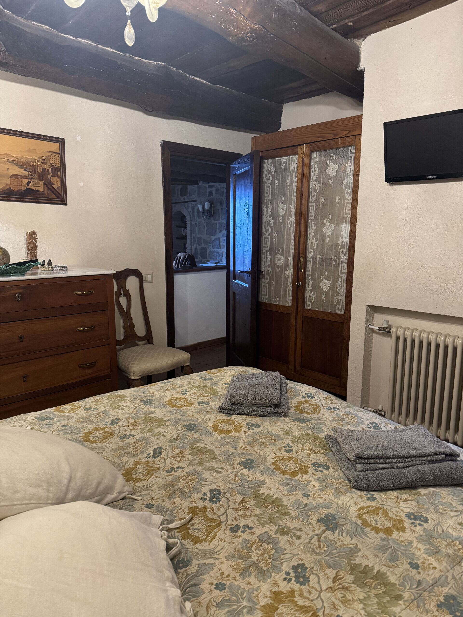 Une chambre à coucher comprenant un lit, une commode, une chaise et une porte donnant sur une salle de bain.