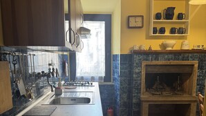 Een keuken met een centraal eiland, houten kasten, een ingebouwde kookplaat en een stenen open haard.