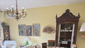 Een eetkamer met een houten tafel, stoelen, een kroonluchter en een grote spiegel.