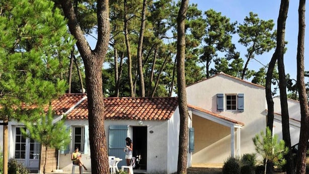 A single-story house with a tiled roof, a front porch, and a small patio area. - House in Vendee Near Les Conches Beach (Longeville-sur-Mer)