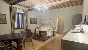 Un vaste espace de vie doté d’un plafond en bois, d’une table à manger avec des chaises, d’un canapé et d’un coin cuisine avec un plan de travail et des appareils électroménagers.